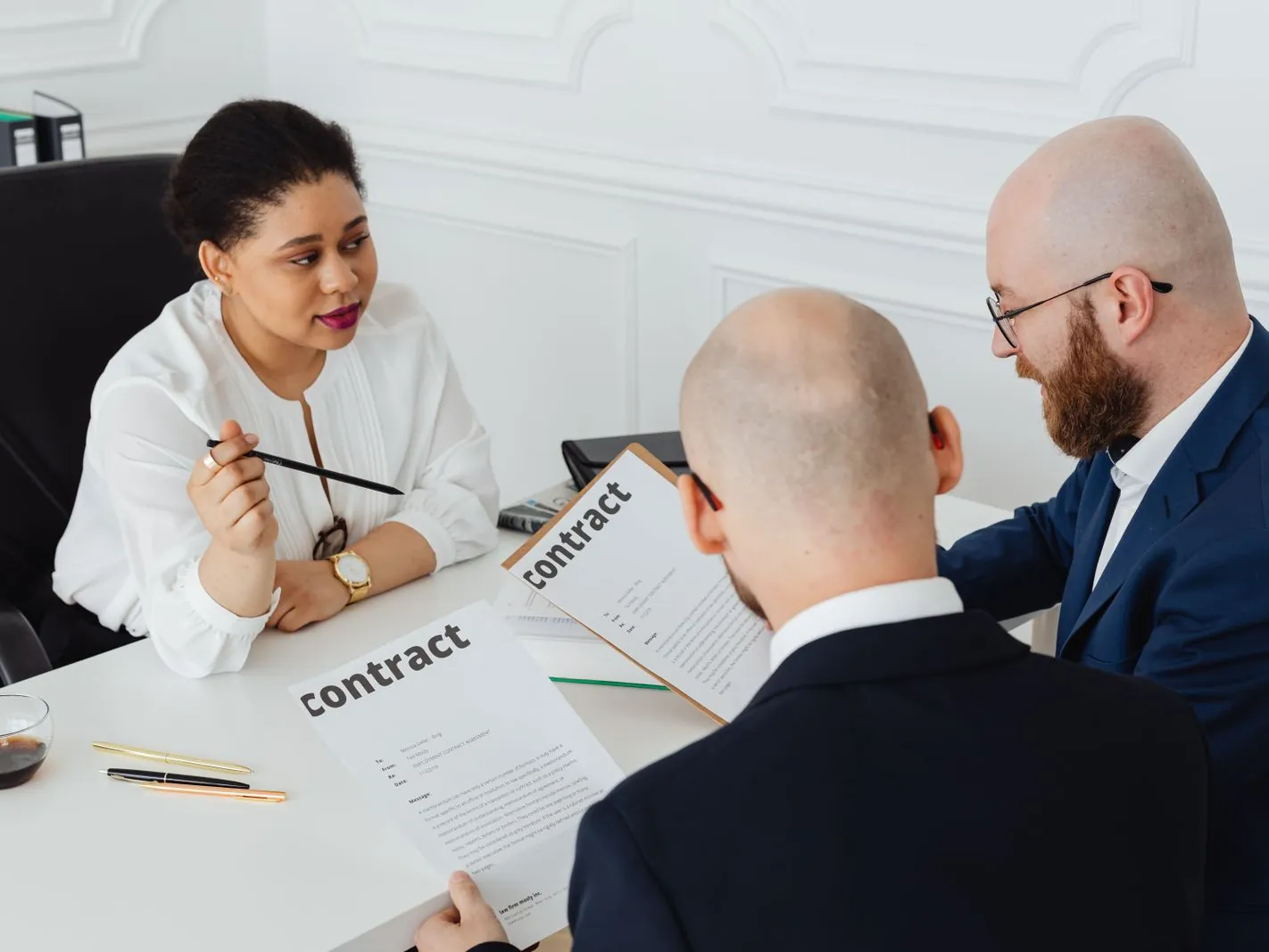 Tres profesionales revisando un contrato en una mesa de reuniones
