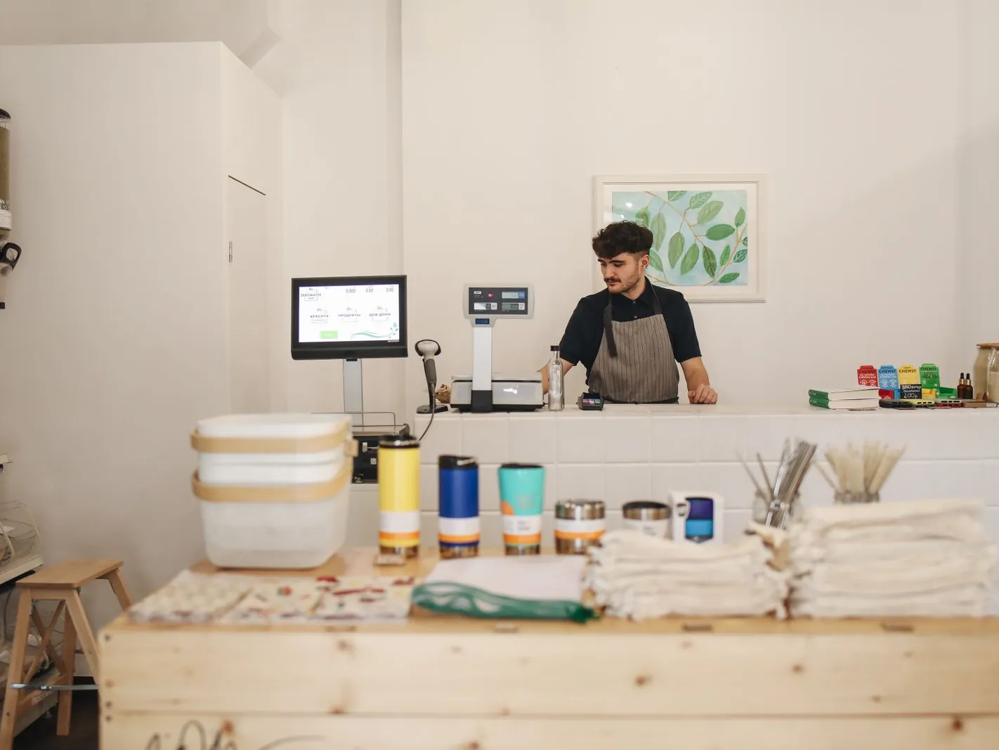 Dependiente atendiendo detrás del mostrador de una tienda con una pantalla de punto de venta